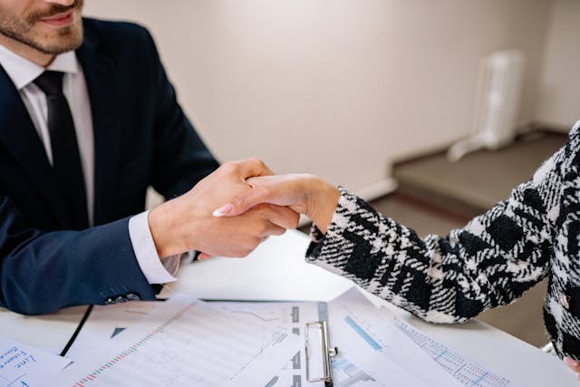 two%20people%20shaking%20hands%20over%20a%20bunch%20of%20financial%20documents two%20people%20shaking%20hands%20over%20a%20bunch%20of%20financial%20documents